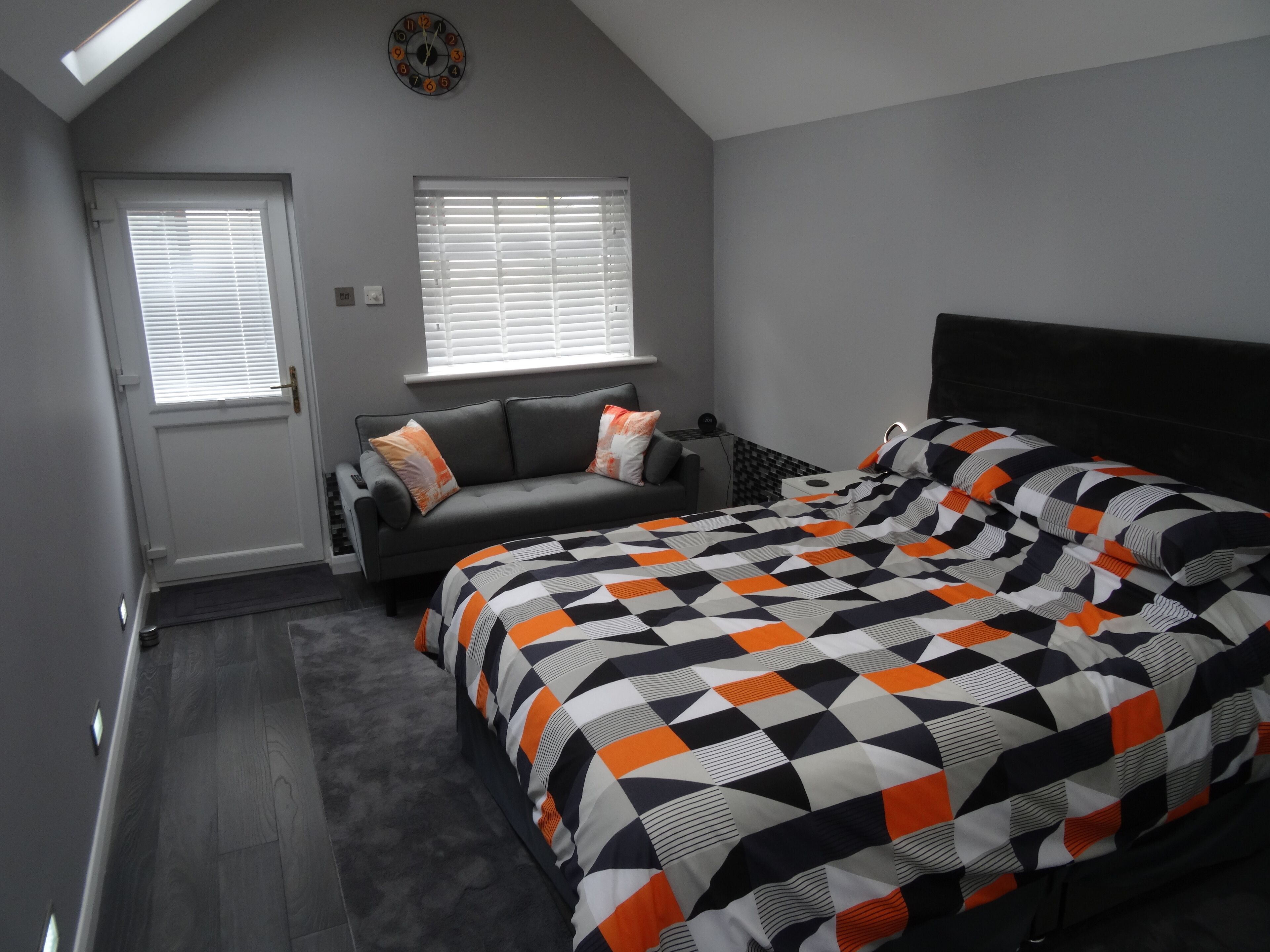 Een slaapkamer met een bed, een bank, een raam en een deur.