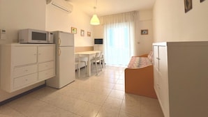 A compact, well-lit room with a kitchenette, a dining area, and a bed. - Perfect Holiday Apartment for Five Guests in Grado (Grado)