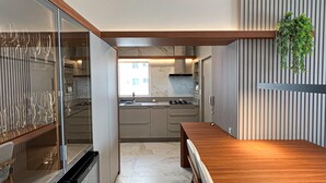 A modern kitchen with a built-in oven, a sink, and a wooden dining table. - New apartment in the heart of Balneário Camboriú. Comfort and sophistication in the best location. (Balneário Camboriú)