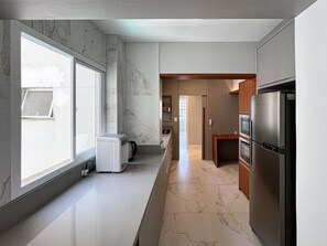 A modern kitchen with a large window, a built-in oven, and a refrigerator. - New apartment in the heart of Balneário Camboriú. Comfort and sophistication in the best location. (Balneário Camboriú)