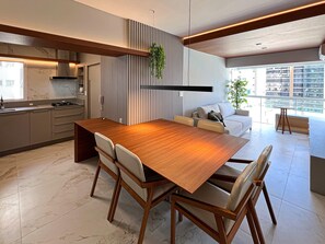 Une cuisine moderne avec une table à manger en bois, des placards intégrés et une grande fenêtre donnant sur la ville.