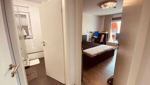 Une chambre à coucher avec un lit, un bureau avec un ordinateur et une salle de bain avec un miroir et un lavabo.