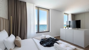 Habitación de hotel con cama, televisión y vista al mar.
