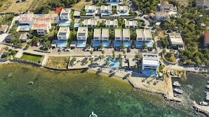 Vista aérea de un resort con varias villas, una piscina y un puerto deportivo.