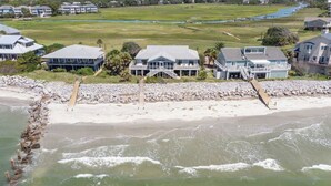 Une propriété située sur la côte, avec une plage, une grande maison à plusieurs étages et un rivage rocheux.