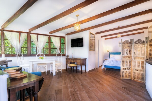 A room with wooden beams, a desk, a chair, a bed, and a TV.