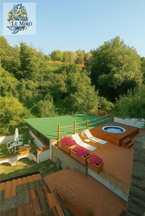 Terraço no telhado com cobertura verde, deck de madeira e uma banheira de hidromassagem.