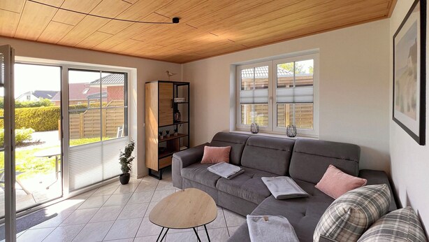 A cozy living room with a grey sofa, a small round table, and a bookshelf.