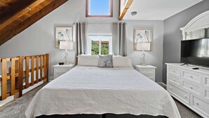 Una camera da letto con un letto grande, due comodini, una TV e una finestra con tende.