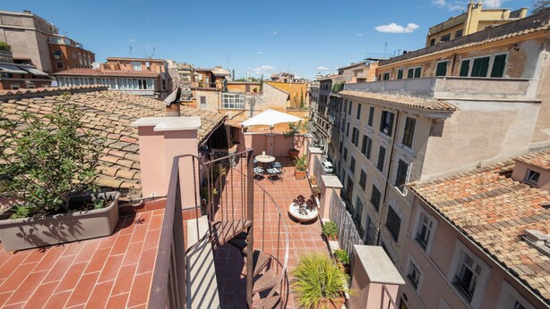 A rooftop terrace with a spiral staircase, potted plants, and outdoor furniture. - Casa Mia - Trastevere Rooftop Loft (Roma)