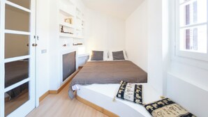 A bedroom with a bed, a window, and built-in shelving. - Casa Mia - Trastevere Rooftop Loft (Roma)