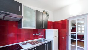A modern kitchen with red tiles, a white refrigerator, and black cabinets. - Casa Mia - Trastevere Rooftop Loft (Roma)