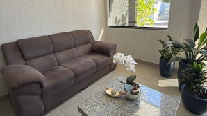 A modern living room with a brown sofa, a granite coffee table, and potted plants. - Hotéis Tropical Aquidauana (Aquidauana)