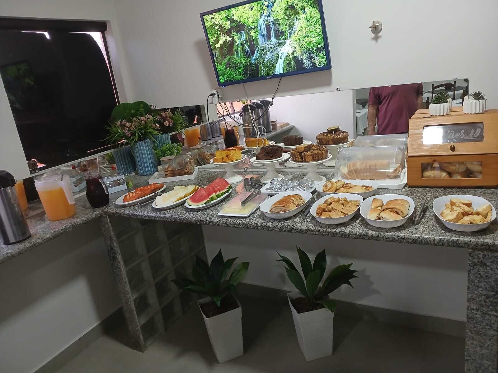 A breakfast buffet with various food items and a television displaying a nature scene.