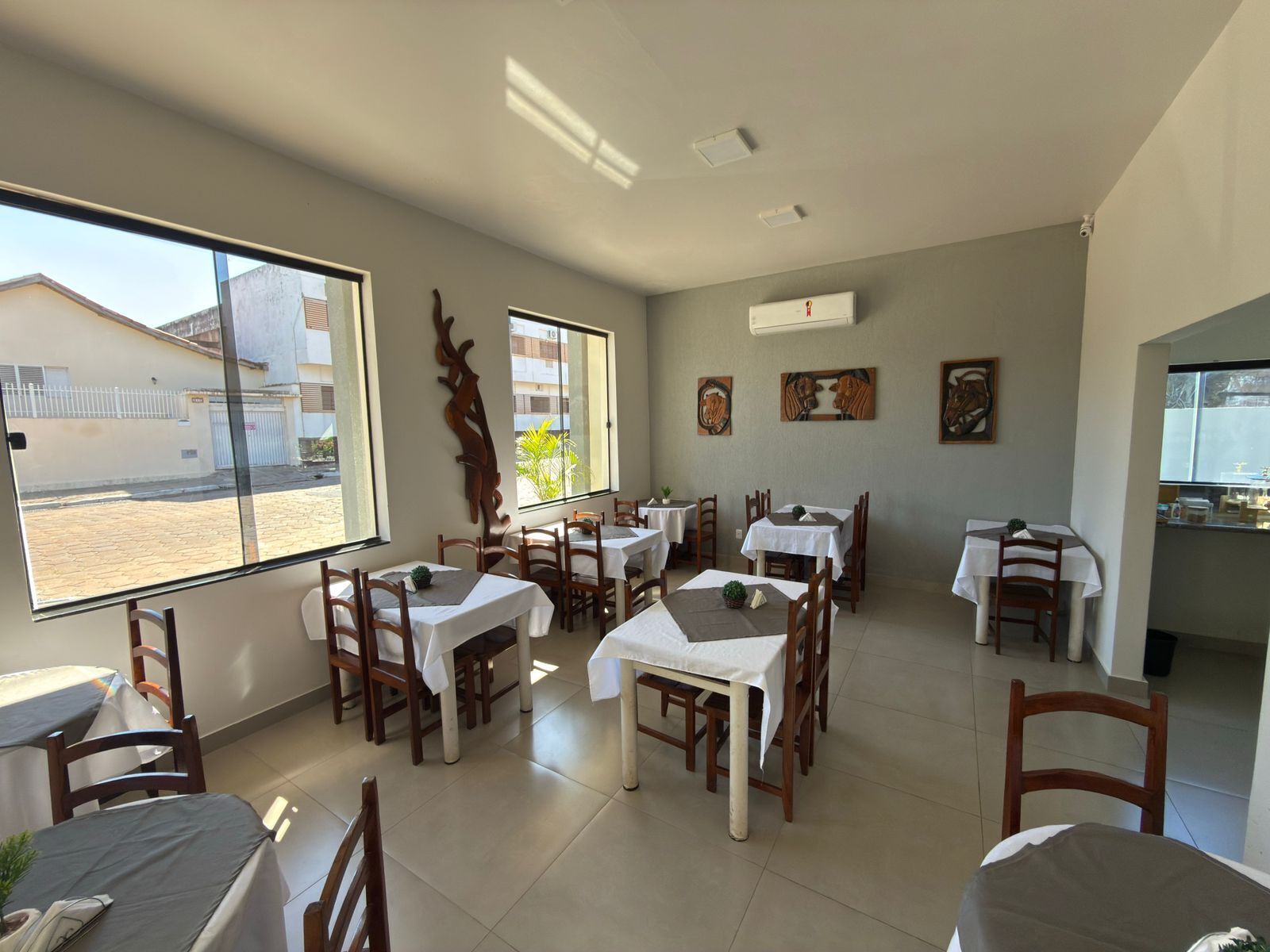 A restaurant with multiple tables, chairs, and a view of the street outside.