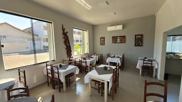 A restaurant with multiple tables, chairs, and a view of the street outside.