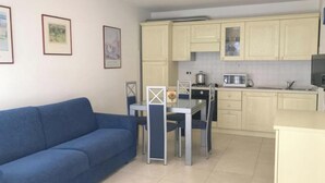 Ein gemütlicher Wohnbereich mit Sofa, Esstisch und Küchenzeile.