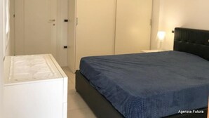 Ein Schlafzimmer mit Bett, Kleiderschrank und Nachttisch mit Lampe.