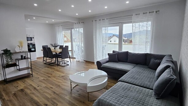 En moderne stue med en modulsofa, et rundt sofabord og et spiseområde med bord og stole.