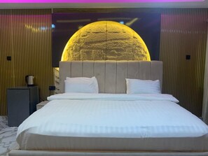 A hotel room with a large bed, a flat-screen TV mounted on the wall, and a wooden panel design on the walls.