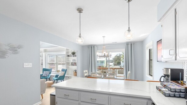 A modern kitchen with white cabinetry, a marble countertop, and pendant lighting. - Ripple| Golf Cart · Private Beach · Outdoor Living (Emerald Isle)