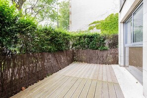 A wooden deck with a white wall and a window on the right. - A Haven of Peace in Neuilly sur Seine (Neuilly-sur-Seine)