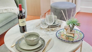 A round table with a bottle of wine, clear glasses, plates, and cutlery. - Historical Apartment in the Heart of Paris - 3 (Paris)