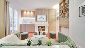 A modern living room with a sofa, a dining table with a vase and a bottle, and a kitchen in the background. - Historical Apartment in the Heart of Paris - 3 (Paris)