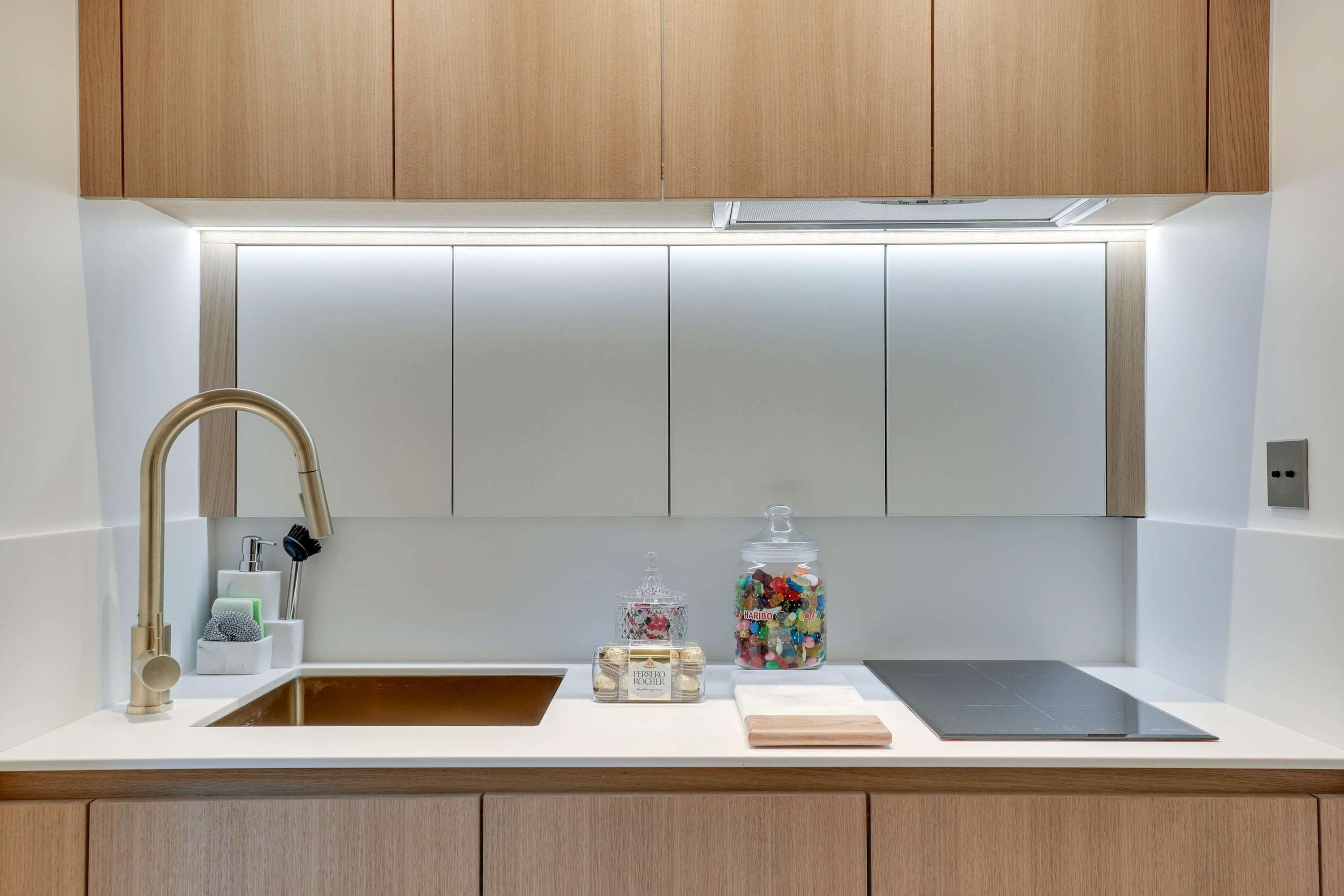 A modern kitchen with wooden cabinets, a stainless steel sink, and a black countertop.