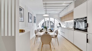 A modern kitchen with white cabinetry, a marble countertop, and a large window. - Historical House in the Heart of Paris - 5 (Paris)