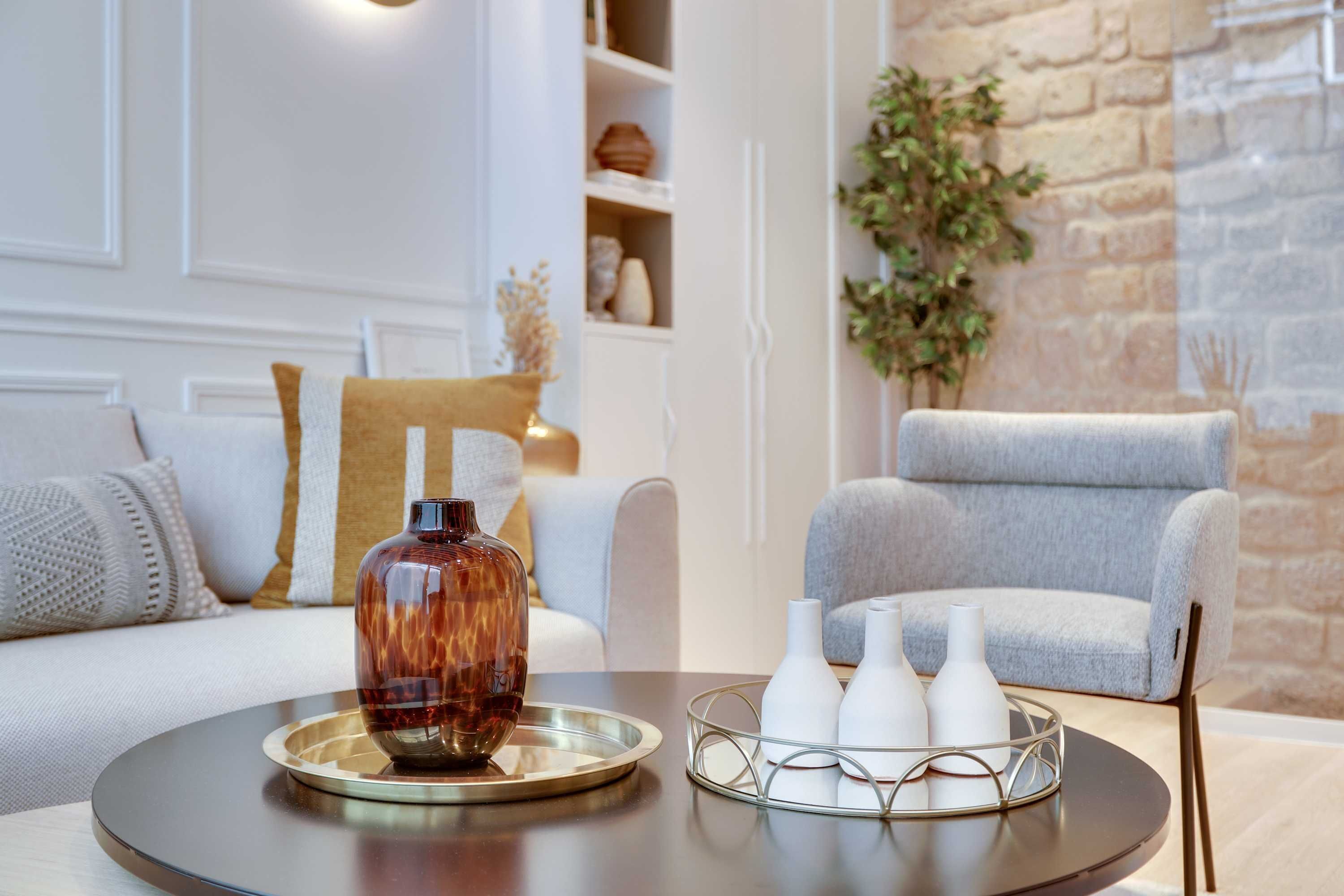 Una sala de estar moderna con un sofá, una mesita de centro y jarrones decorativos.