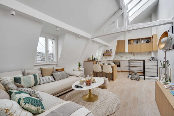Un vaste appartement de type « loft » comprenant un espace de vie, une cuisine et un coin repas.
