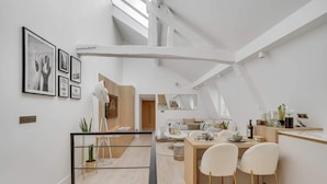 A modern kitchen with a dining area, featuring a wooden table, white chairs, and a large window. - Historical Apartment in the Heart of Paris - 4 (Paris)