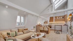 A modern loft apartment with a high ceiling, a cozy living area with a sofa and coffee table, a kitchen with wooden cabinets, and a dining area. - Historical Apartment in the Heart of Paris - 4 (Paris)