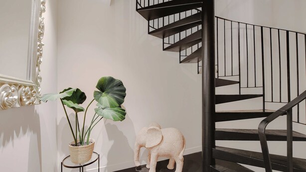 En trappa med modern design, en dekorativ spegel och en krukväxt.