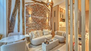 A modern living room with a brick wall, a round marble table, two sofas, and a wooden partition. - Historical Apartment in the Heart of Paris (Paris)