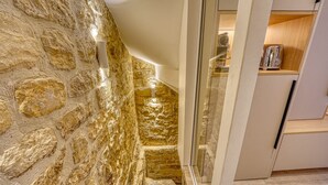 A kitchen with stone walls, a glass door, and wooden cabinets. - Historical Apartment in the Heart of Paris (Paris)