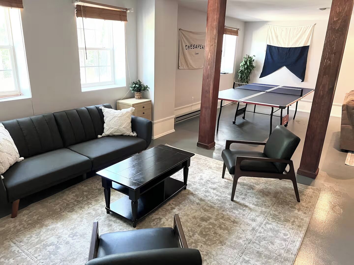 A living room with a sectional sofa, a coffee table, a chair, and a ping pong table.