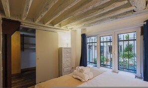 Un dormitorio con una cama grande, un aparador y vistas a un patio a través de una ventana.