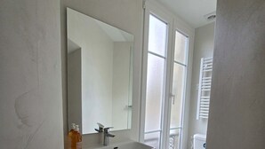 Een moderne badkamer met een wit wastafelmeubel, spiegel en toilet.