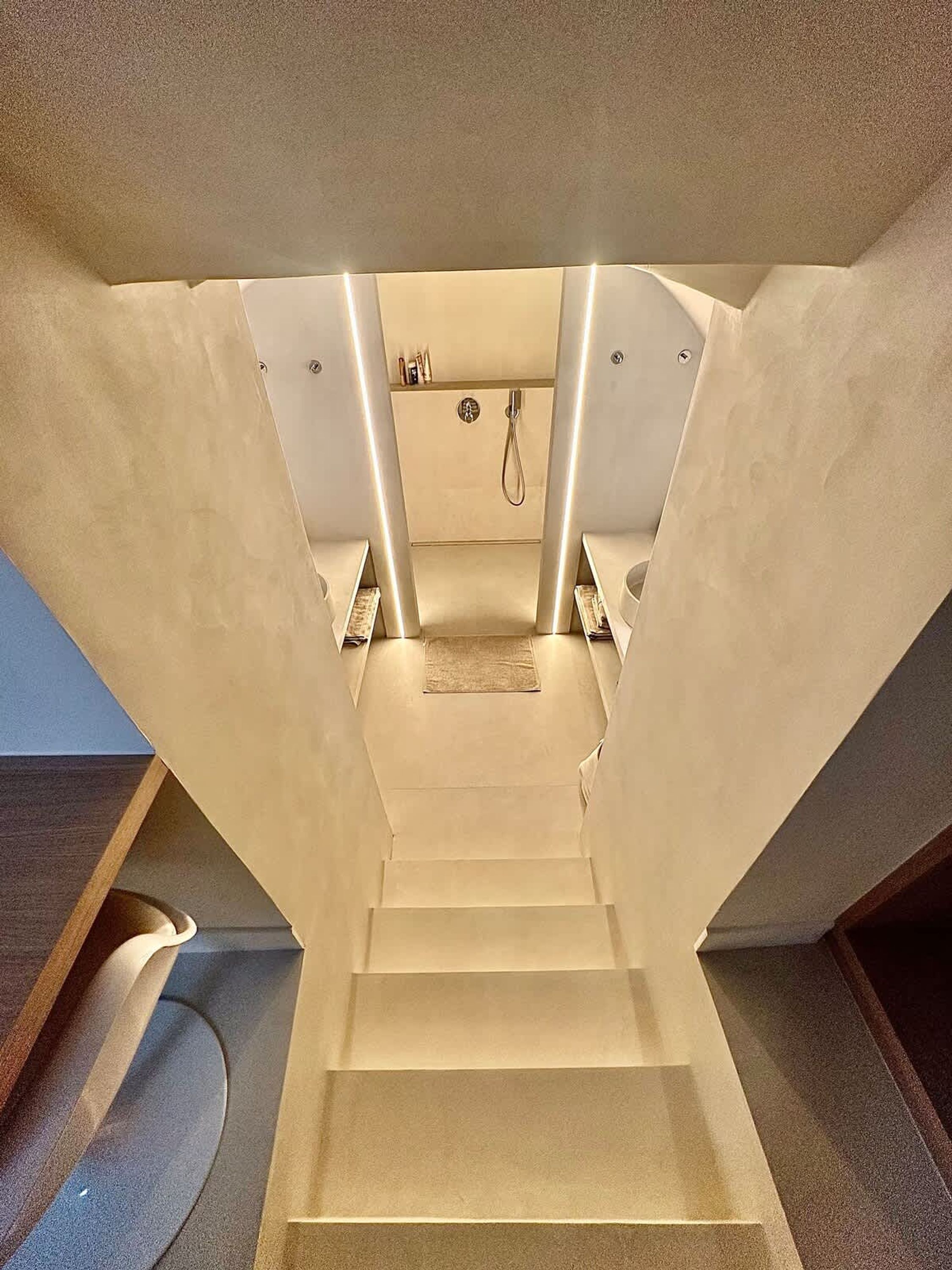 Una escalera moderna con un diseño minimalista que lleva a un baño con ducha y toallero.