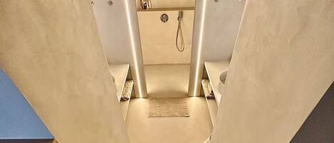 Una escalera moderna con un diseño minimalista que lleva a un baño con ducha y toallero.