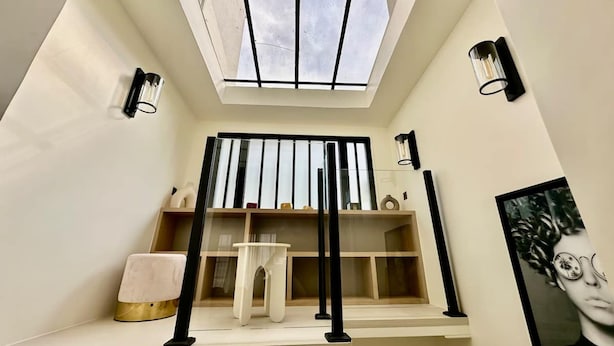 A room with a skylight, a desk, shelves, a chair, and two wall-mounted lamps. - Magnifique Loft Luxe Montmartre Climatis (Paris)