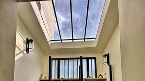 A compact, modern room with a skylight, built-in shelving, and a spiral staircase. - Magnifique Loft Luxe Montmartre Climatis (Paris)