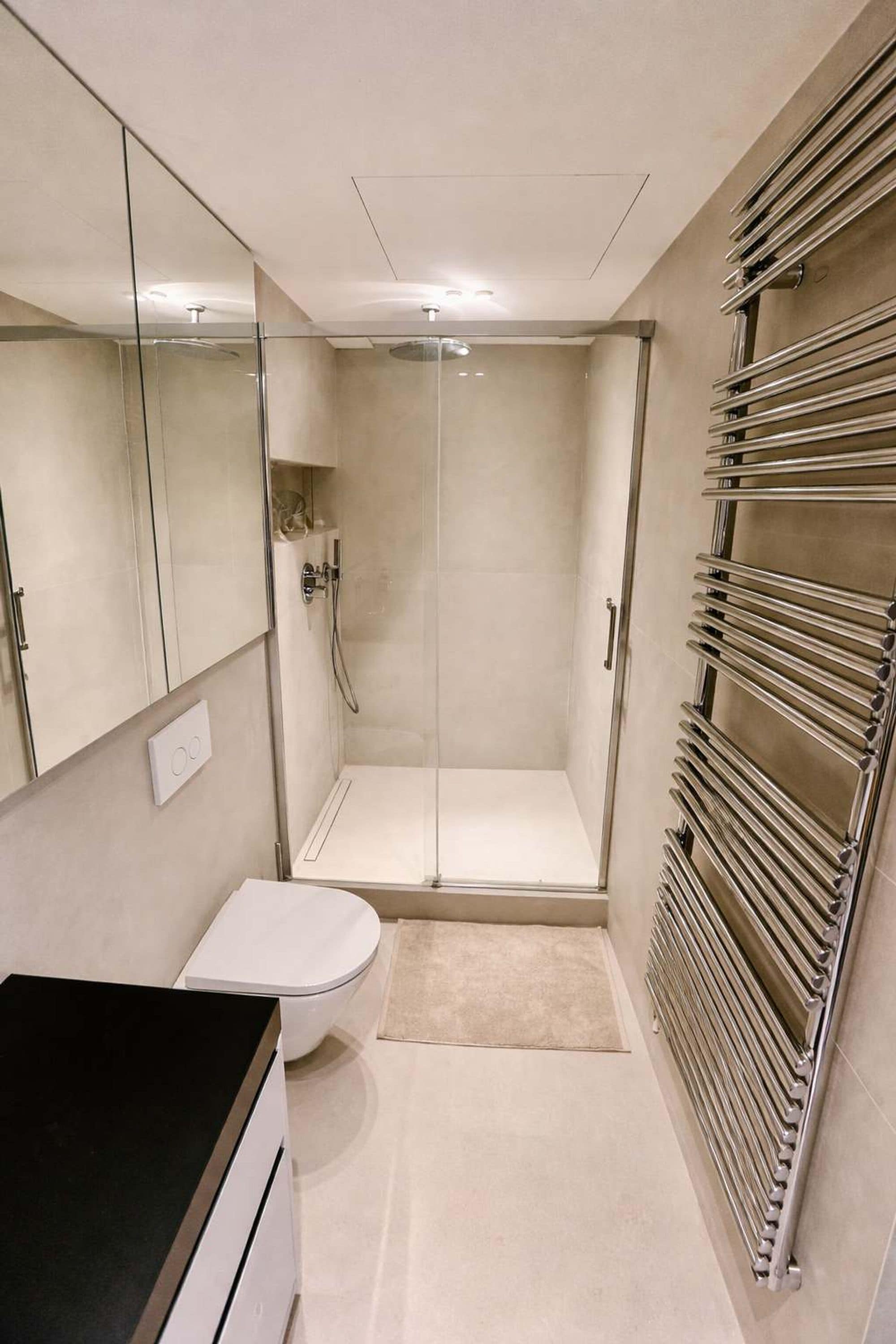 Ein modernes Badezimmer mit einer gläsernen Duschkabine, Toilette und integriertem Waschbecken.