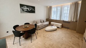 A modern living room with a dining area, a sofa, a coffee table, and a large window with curtains. - Magnifique Loft Luxe Montmartre Climatis (Paris)