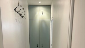 A narrow hallway with a wooden floor, a light green double door at the end, and a wall-mounted light fixture on the left. - Flat Near Notre Dame 4 pax AC (Paris)