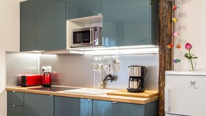 A modern kitchen with a microwave, coffee maker, and kettle on the countertop. - Place des Vosges Havre de Paix Paris 8 Pers AC (Paris)
