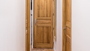 A narrow hallway with wooden doors on either side and a tiled floor. - Place des Vosges Havre de Paix Paris 8 Pers AC (Paris)