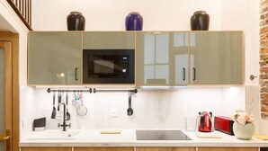 A kitchen with a microwave, cabinets, and a sink. - 1st District Louvre Notre Dame 8 Guests - AC (Paris)